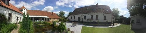 a building with a brown roof and a person on a bike in front of it at Cense de Lalouette in Saint-Ghislain