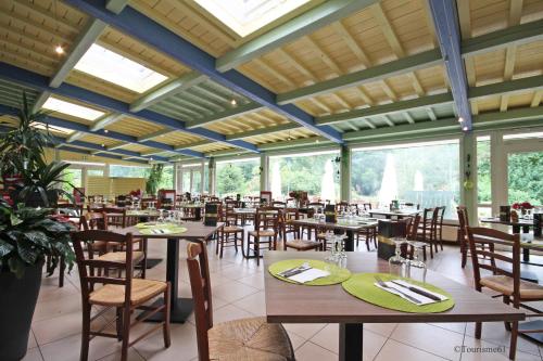 a dining room with tables and chairs and windows at Logis Hôtel De France in Domfront