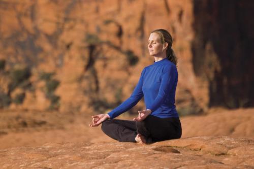 a woman sitting on a rock doing yoga at Red Mountain Resort in St. George