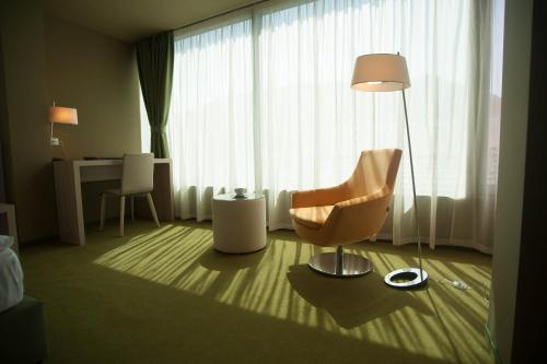 a room with a chair and a lamp and a desk at Hotel Armatti in Braşov