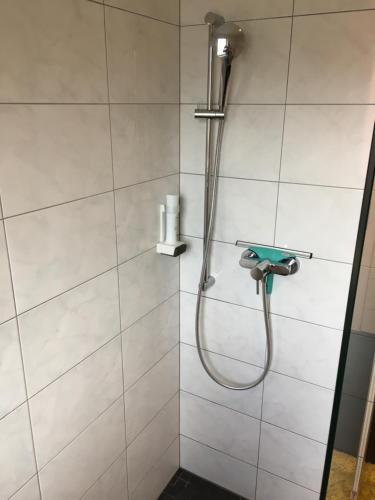 a shower with a hose in a white tiled bathroom at Wirtshaus zum Stern in Satteins