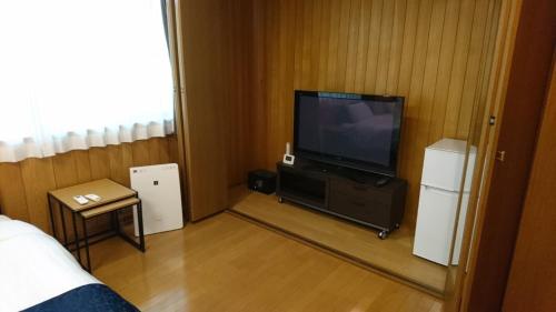 a hotel room with a television and a bed and a room at Minpaku Nagashima room3 / Vacation STAY 1035 in Kuwana
