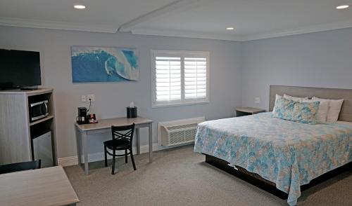 sypialnia z łóżkiem, biurkiem i telewizorem w obiekcie Surf City Inn w mieście Huntington Beach