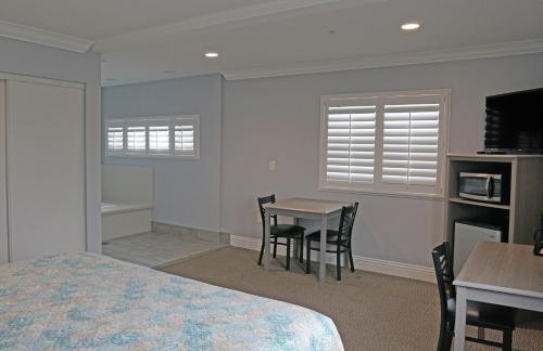 a bedroom with a bed and a table and chairs at Surf City Inn in Huntington Beach
