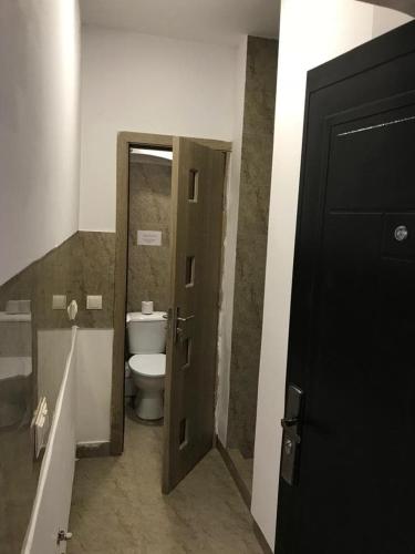 a bathroom with a toilet and a open door at Regim Hotelier Pietonală in Oradea