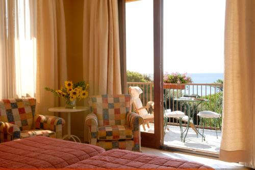a room with a bed and chairs and a balcony at Roccamare Resort - Casa di Ponente in Castiglione della Pescaia