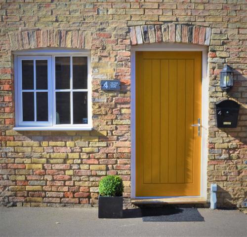 a yellow door and a window on a brick building at The Old Bottle Store - 2 Double Bedrooms, 2 Bathrooms, St Ives, Cambridgeshire in St. Ives