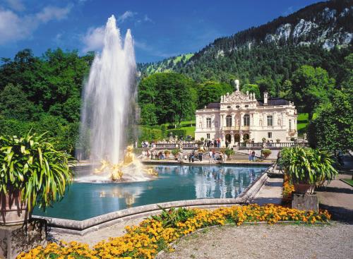 a fountain in front of a building with a mansion at Am-Berg Ferienwohnung in Bad kohlgrub in Bad Kohlgrub