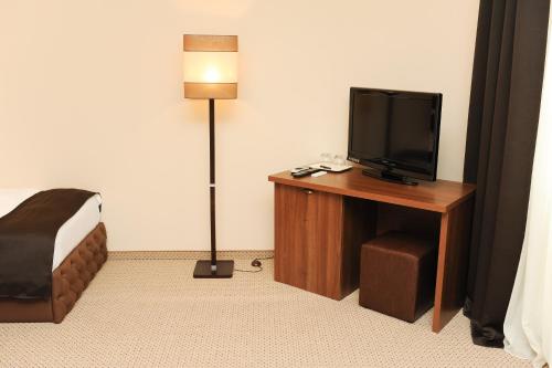 Habitación de hotel con TV y escritorio con lámpara. en Vine Rooms en Oradea