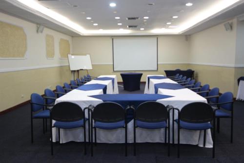 a conference room with tables and chairs and a whiteboard at Hotel Castilla Real in Pereira