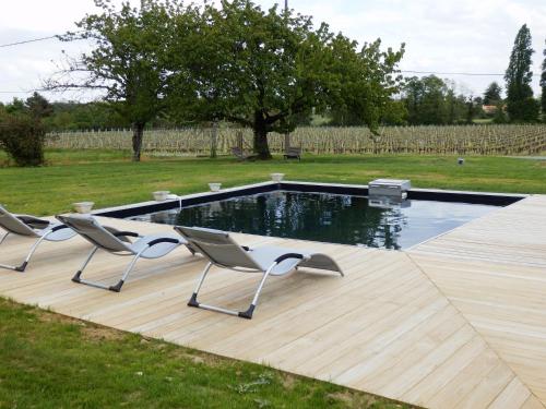 - une piscine avec 2 chaises sur une terrasse en bois dans l'établissement Chateau La Mothe du Barry, à Moulon-sur-Dordogne