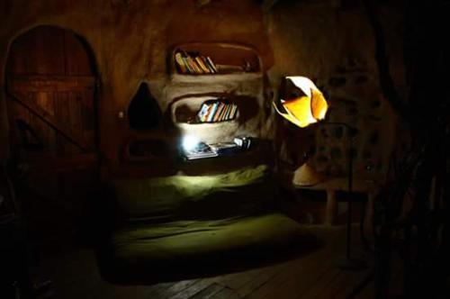 Habitación oscura con silla y lámpara en Hobbit House en Tandil