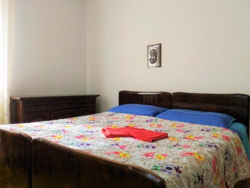 a bed with a flowered comforter with a red shirt on it at MELAX Apartment in Tassullo