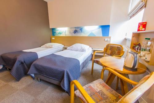 Zimmer mit 2 Betten, einem Tisch und Stühlen in der Unterkunft Hotel Platan in Ostrowo