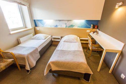 a hospital room with two beds and a desk at Hotel Platan in Ostrów Wielkopolski