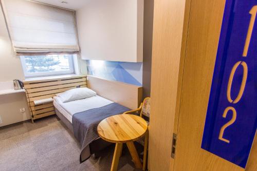 a small room with a bed and a table at Hotel Platan in Ostrów Wielkopolski