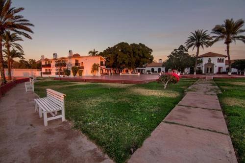 a park with a white bench in front of a house at Hotel Playa de Cortes in Guaymas