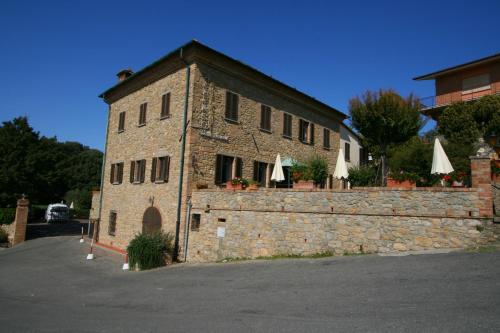 an old brick building with a stone wall and tables at Villa Nencini in Volterra