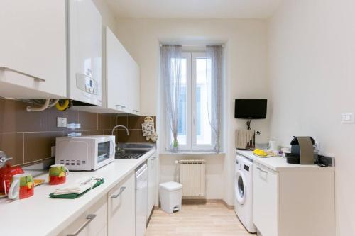 a kitchen with white cabinets and a microwave at Alla Scalinata del Teatro Rossetti parcheggio in Trieste