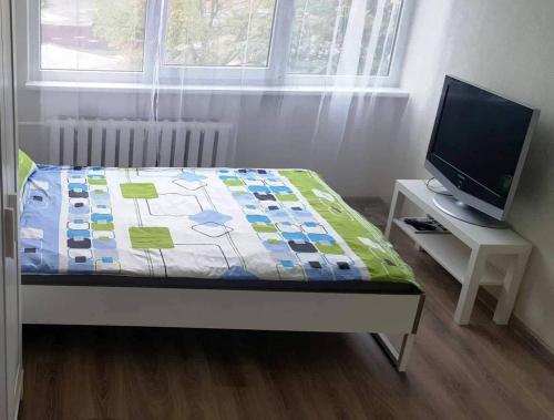 Cette chambre comprend un lit avec une couette et une télévision. dans l'établissement Apartment for You, à Klaipėda