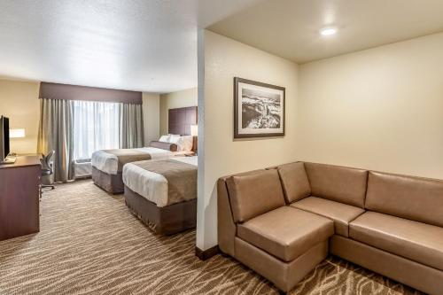 a hotel room with two beds and a couch at Cobblestone Hotel & Suites Hartford in Hartford