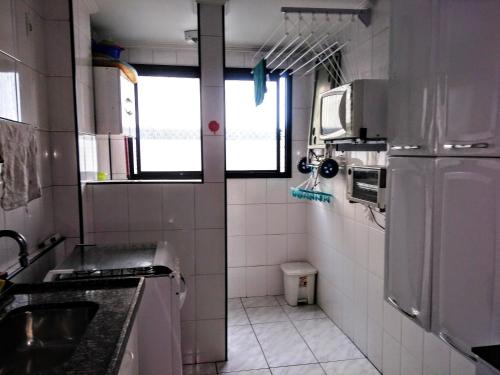 a small kitchen with a sink and a refrigerator at Apartamento na praia do Itarare in São Vicente
