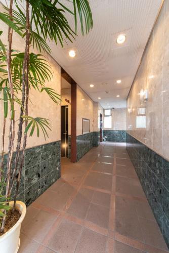 a hallway with a palm tree in a building at Grande Famille Shimanouchi Dotonbori Condo in Osaka