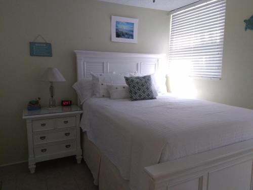 Un dormitorio con una cama blanca y una ventana. en Sea Palm E, en Fort Walton Beach