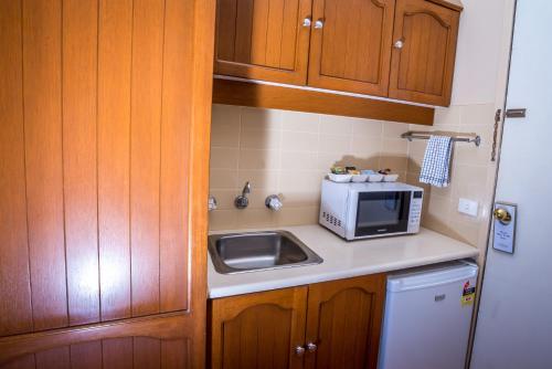 a kitchen with a microwave and a sink at Town Beach Motor Inn Port Macquarie in Port Macquarie