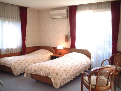 a bedroom with two beds and a table and chairs at Pension Candytuft in Karuizawa