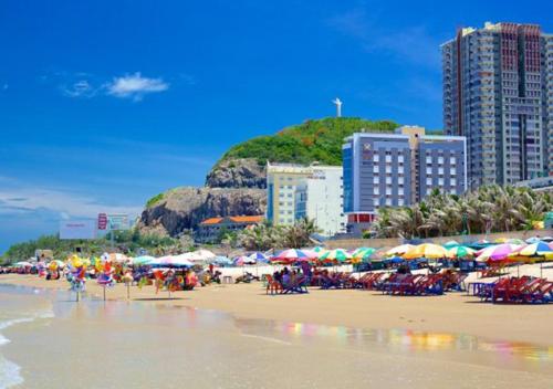 - une plage avec des parasols et des personnes assises sur la plage dans l'établissement Khách Sạn Quốc Cường-Dì Tám, à Vung Tau