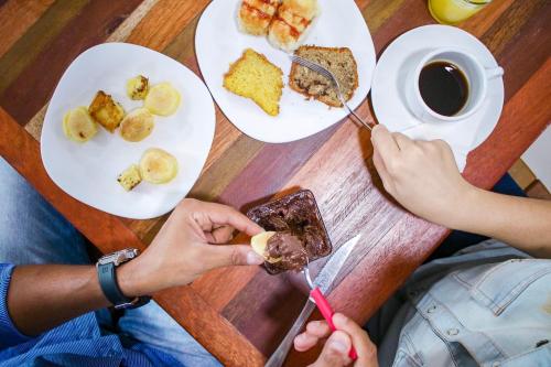 two people eating food at a table with plates of food at Oriental Praia Hotel in João Pessoa