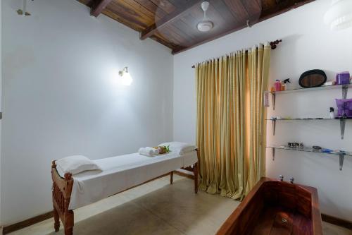 a bedroom with a bed and a yellow curtain at Hotel Sobana Lake front in Udawalawe