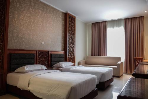 Habitación de hotel con 2 camas y sofá en Onih Hotel en Bogor