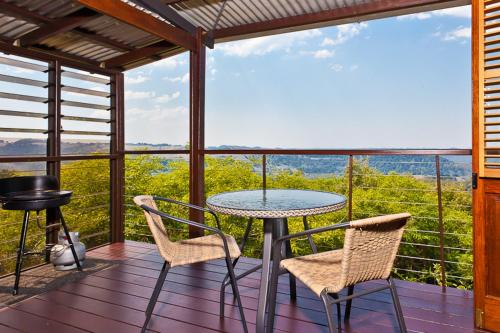 a patio with a table and chairs on a balcony at Rosebrook Cottages in Maleny