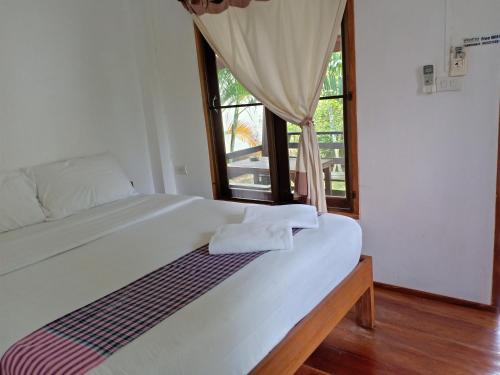 a bedroom with a large white bed with a window at paibaansuan in Pai