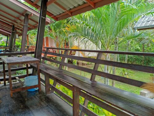 a wooden bench on a porch with palm trees at paibaansuan in Pai