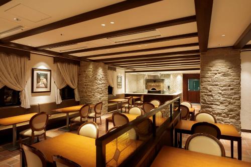 a restaurant with tables and chairs and a stone wall at Hotel Mori no Kaze Nasu in Nasu