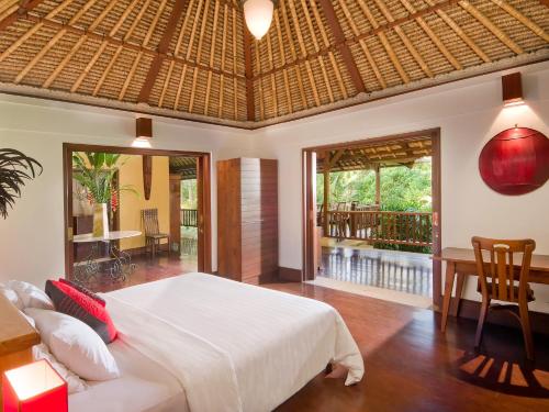a bedroom with a large white bed and a balcony at Villa Alamanda in Ubud
