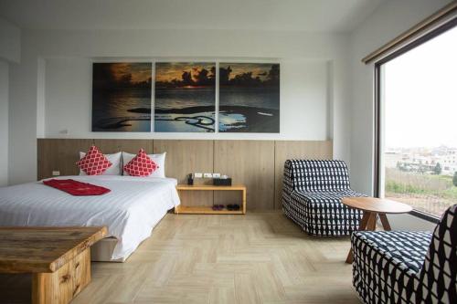 a bedroom with a bed and a table and a chair at Hsu One One B&B in Magong