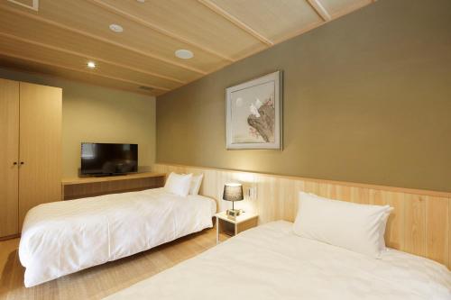 two beds in a room with a tv and a bed sidx sidx sidx at Hotel Shiki no Yakata Nasu in Nasu