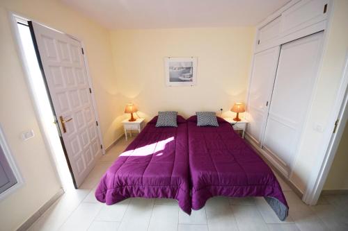 プエルト・デ・サンティアゴにあるPunta N 6 - Vivienda vacacionalのランプ2つが備わる客室の大きな紫色のベッド1台