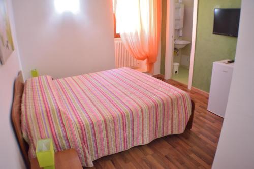 a small bedroom with a bed with a striped blanket at Borgo Saraceno in Spinazzola