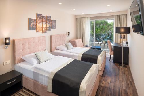 a hotel room with two beds and a desk at Hotel Central Beach 9 in Makarska