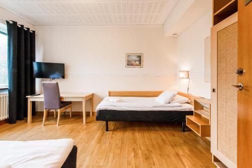 Holmsund的住宿－Västerbacken Hotell & Konferens，酒店客房配有一张床、一张桌子和一把椅子。