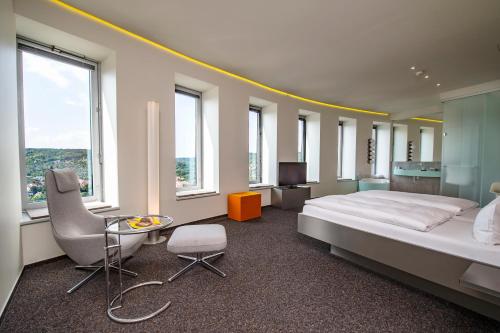 um quarto com uma cama, uma cadeira e janelas em Scala Turm Hotel Restaurant em Jena