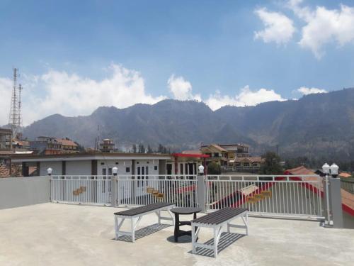 two benches sitting on a balcony with mountains in the background at Bromo Otix Guest House in Bromo