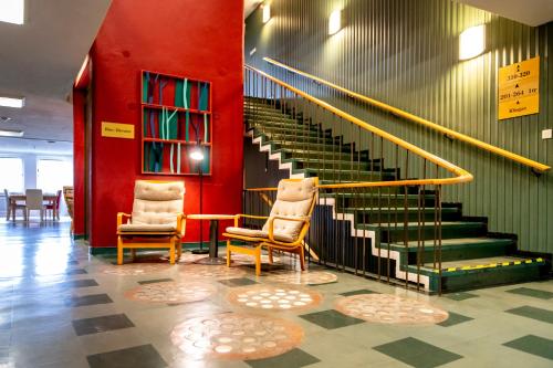 two chairs and a staircase in a room with red walls at Västerbacken Hotell & Konferens in Holmsund
