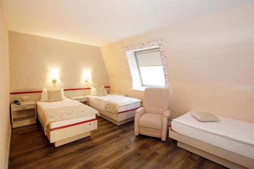 a room with two beds and a chair in it at Hotel Märkischer Hof in Luckenwalde