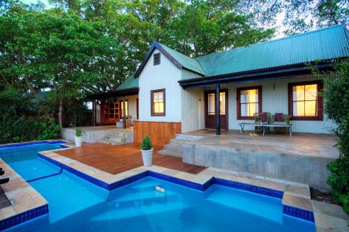 a house with a swimming pool in front of a house at Camp Figtree by The Oyster Collection in Addo